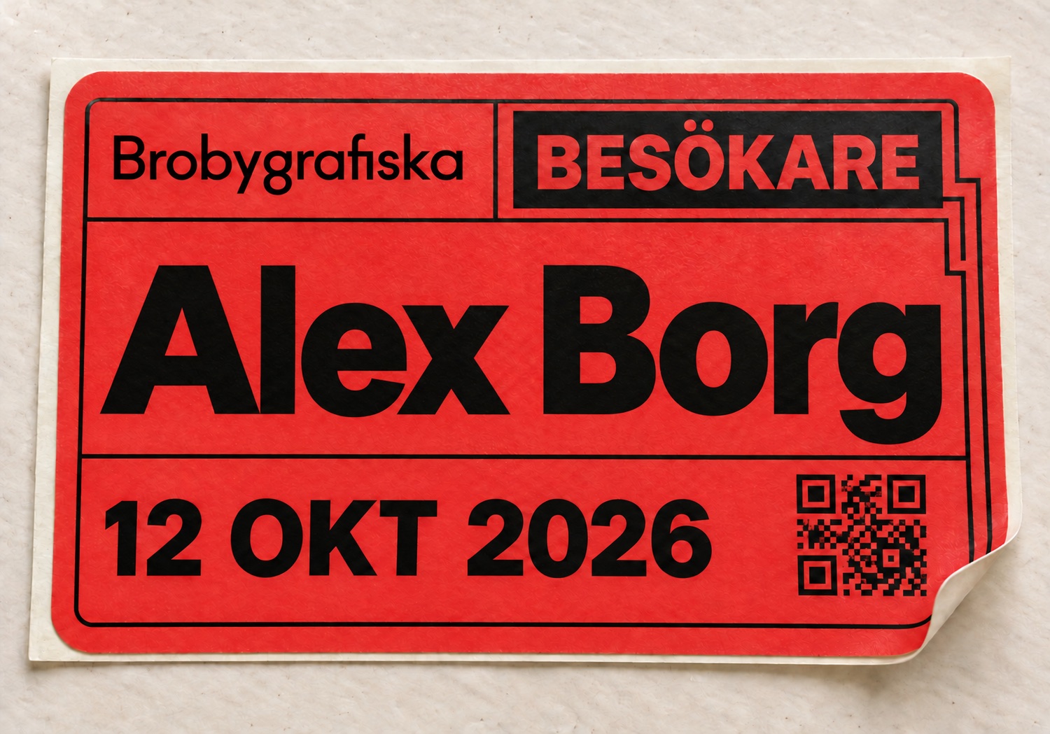 Röd besöksetikett med Brobygrafiskas logotyp, BESÖKARE, Alex Borg, 12 oktober 2026 och QR-kod.