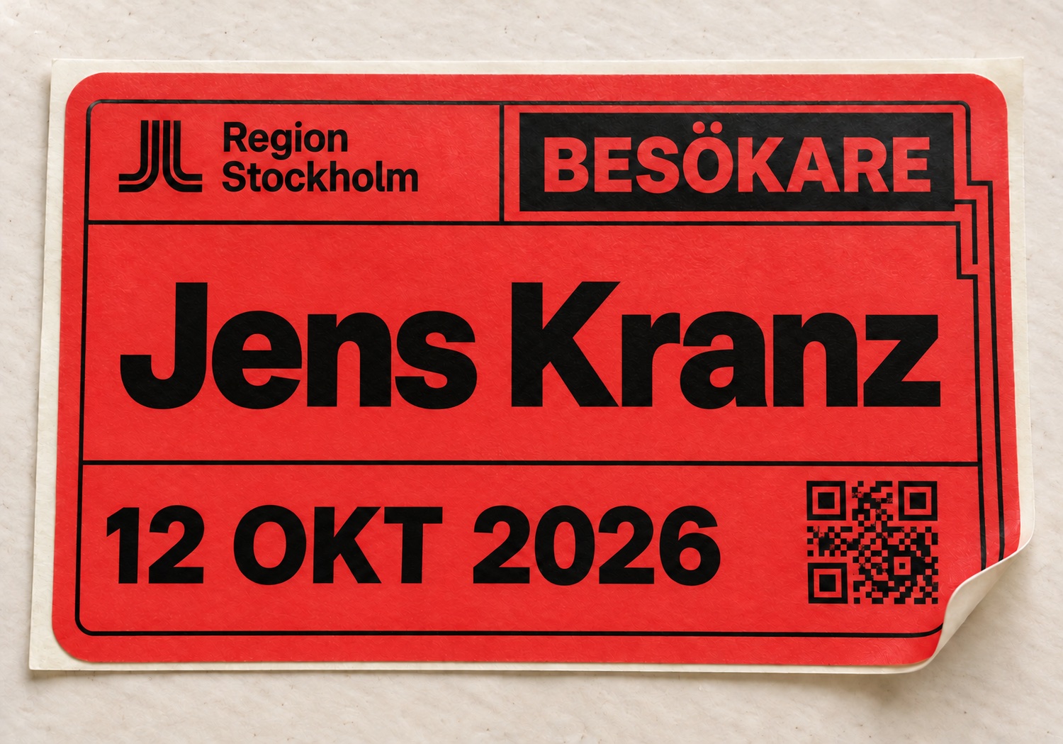Röd besöksetikett med Region Stockholms logotyp, BESÖKARE, Jens Kranz, 12 oktober 2026 och QR-kod.